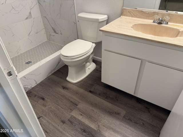 bathroom featuring vanity, hardwood / wood-style floors, toilet, and tiled shower