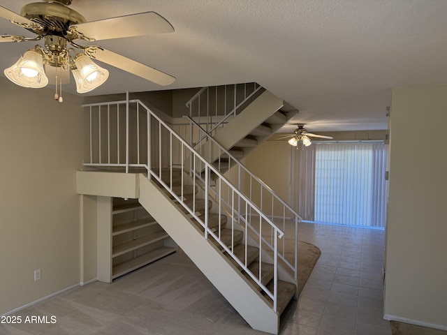 stairway featuring ceiling fan, tile patterned floors, and a textured ceiling