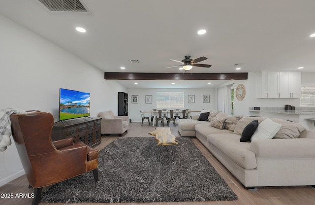 living room featuring ceiling fan, beam ceiling, and light wood-type flooring