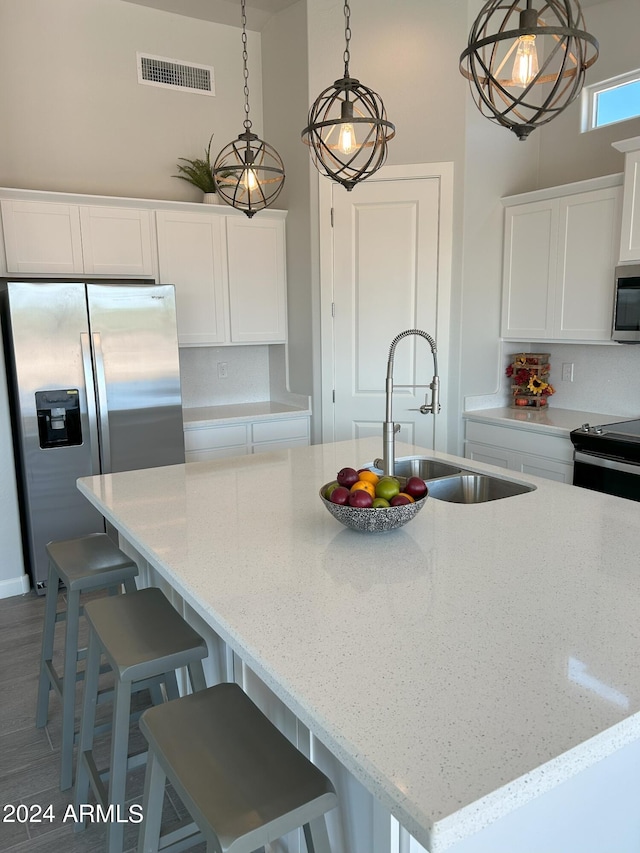 kitchen featuring pendant lighting, sink, stainless steel appliances, and an island with sink