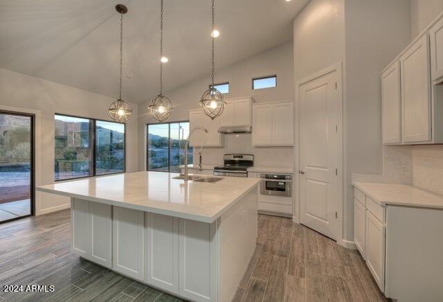 kitchen featuring white cabinetry, sink, stainless steel appliances, an island with sink, and decorative light fixtures