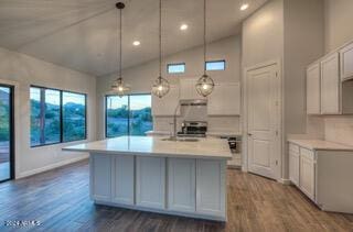 kitchen with pendant lighting, dark hardwood / wood-style flooring, a center island with sink, and lofted ceiling