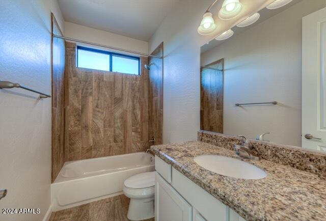 full bathroom featuring tiled shower / bath combo, toilet, and vanity