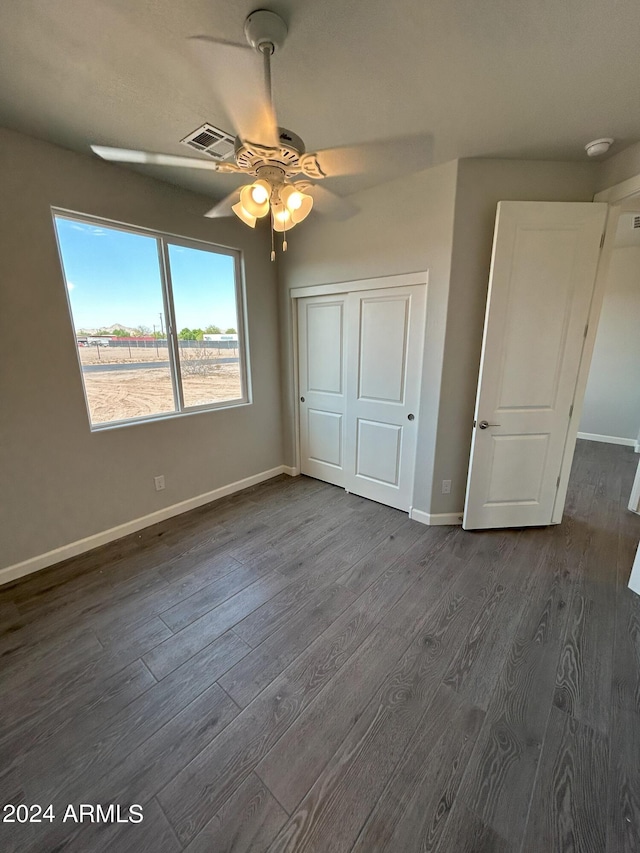 unfurnished bedroom featuring ceiling fan, dark hardwood / wood-style flooring, and a closet