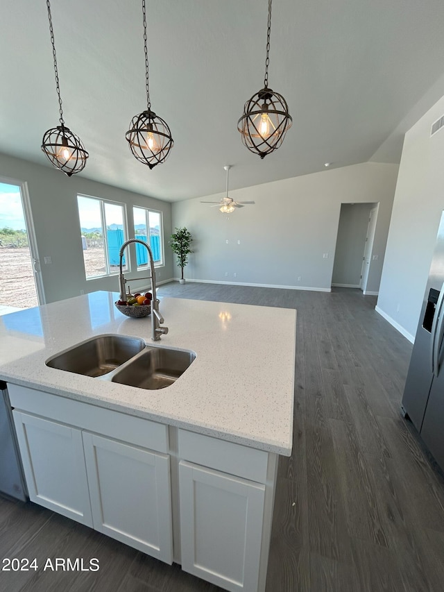 kitchen with light stone countertops, a kitchen island with sink, sink, decorative light fixtures, and white cabinetry