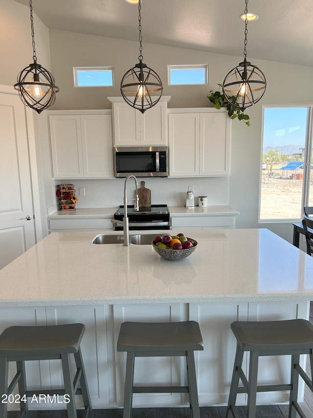 kitchen with decorative light fixtures, white cabinets, stainless steel appliances, and vaulted ceiling