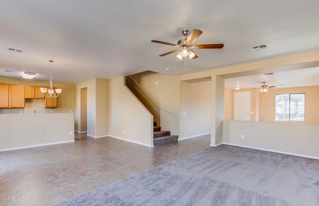 unfurnished living room featuring ceiling fan with notable chandelier