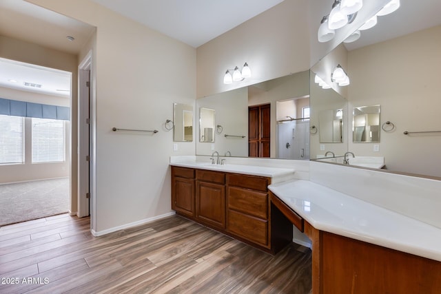 bathroom featuring wood-type flooring, a shower with door, and vanity