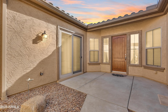 exterior entry at dusk featuring a patio area