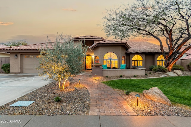 mediterranean / spanish house featuring stucco siding, a garage, driveway, and a tiled roof