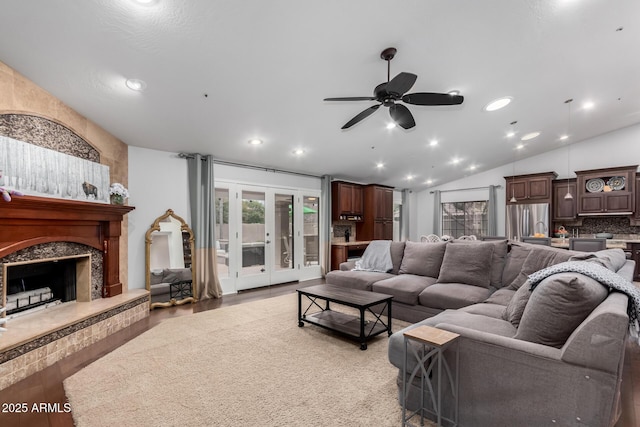 living area with a premium fireplace, light wood-style flooring, recessed lighting, vaulted ceiling, and french doors