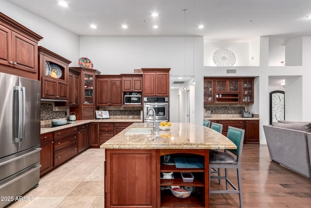 kitchen with a sink, backsplash, a kitchen bar, stainless steel appliances, and open shelves