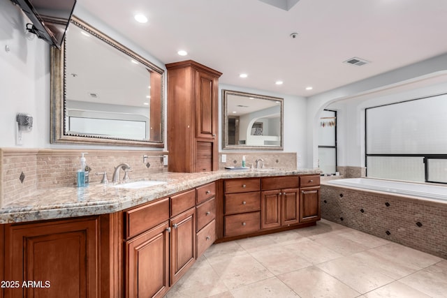 full bath featuring visible vents, backsplash, double vanity, tile patterned floors, and a sink