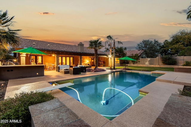 pool at dusk with outdoor lounge area, a patio, a fenced backyard, and a fenced in pool