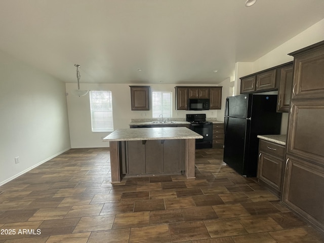 kitchen with a sink, black appliances, light countertops, a kitchen island, and dark brown cabinets