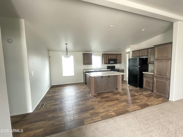 kitchen featuring lofted ceiling, a center island, light countertops, and black appliances