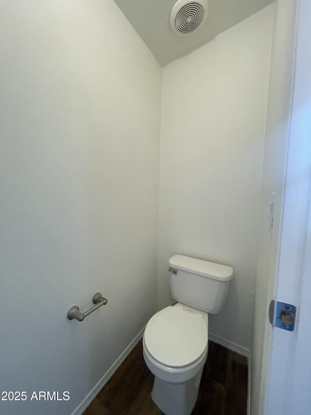 bathroom featuring baseboards, toilet, visible vents, and wood finished floors