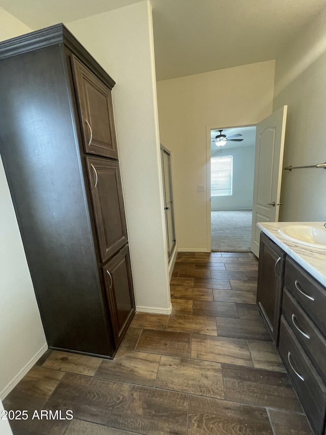 full bath with a ceiling fan, a shower with door, baseboards, vanity, and wood finished floors