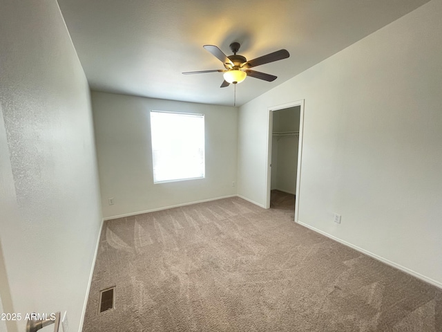 unfurnished bedroom with a walk in closet, carpet floors, baseboards, and visible vents