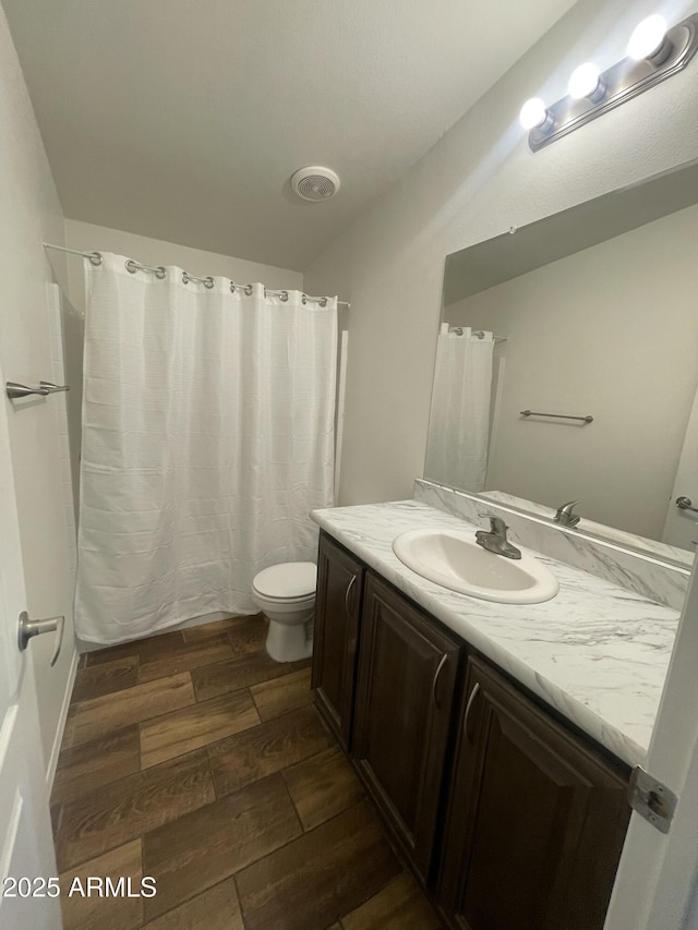 full bath featuring toilet, wood finished floors, vanity, visible vents, and a shower with shower curtain