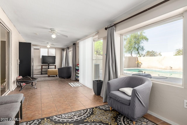tiled living area with a wall mounted air conditioner and ceiling fan