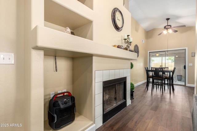 living area with high vaulted ceiling, ceiling fan, a fireplace, dark wood-style flooring, and baseboards