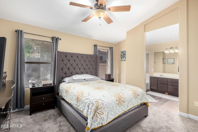carpeted bedroom with ensuite bathroom, baseboards, and a ceiling fan