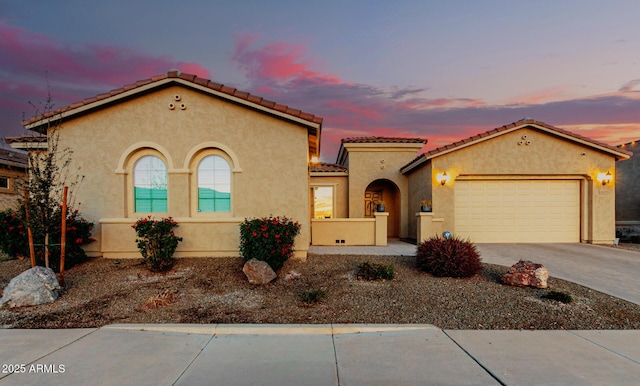 mediterranean / spanish-style home featuring decorative driveway, a tiled roof, an attached garage, and stucco siding