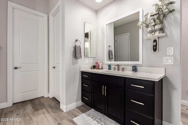 bathroom featuring baseboards, wood finished floors, and vanity