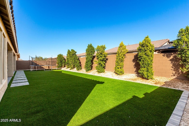 view of yard with a trampoline and a fenced backyard