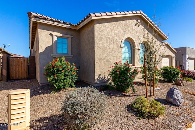 view of front of house with a tiled roof, fence, and stucco siding