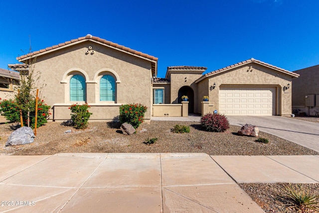 mediterranean / spanish house featuring a garage, driveway, a tiled roof, and stucco siding