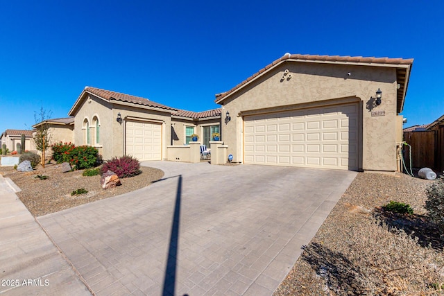 view of front facade featuring a garage, driveway, a tile roof, and stucco siding