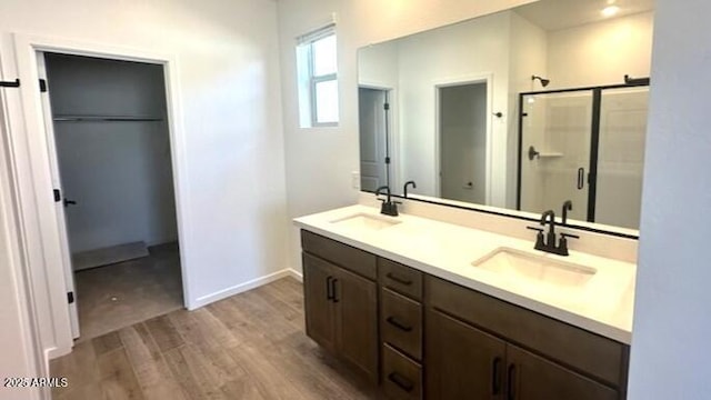 5657 S 253rd Ave, Buckeye, AZ 85326 - full bathroom featuring wood finished floors, double vanity, a shower stall, and a walk in closet
