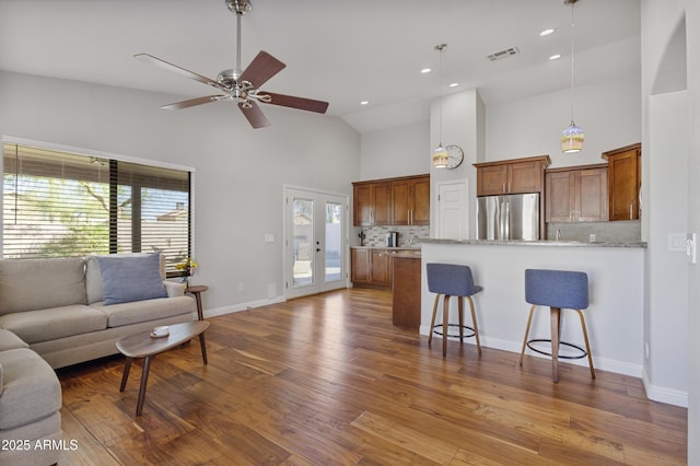 living room with high vaulted ceiling, wood finished floors, ceiling fan, baseboards, and recessed lighting