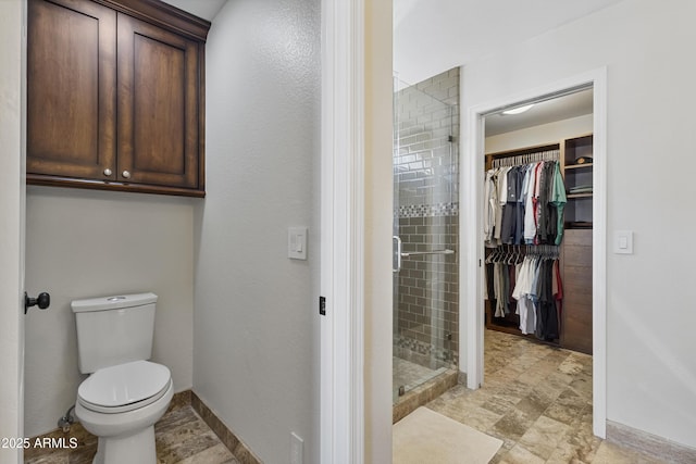 bathroom with a stall shower, a walk in closet, and toilet