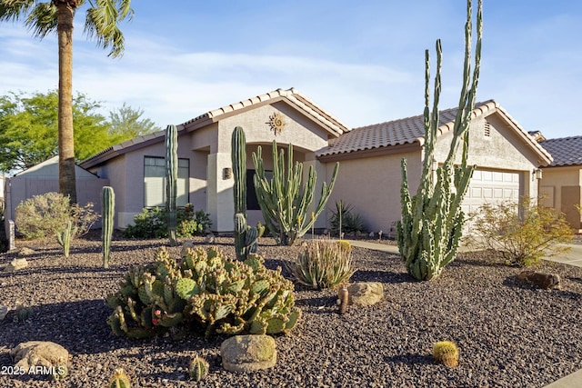 mediterranean / spanish home featuring an attached garage, stucco siding, and a tiled roof
