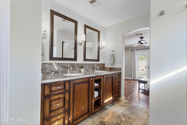 bathroom featuring ceiling fan, double vanity, and baseboards