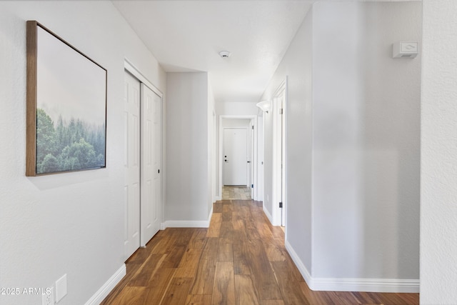 hallway with dark wood-style flooring and baseboards