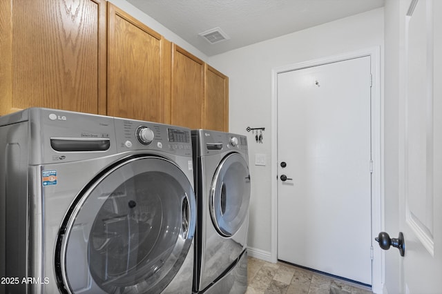 washroom with cabinet space, washer and dryer, baseboards, and light stone finish floors