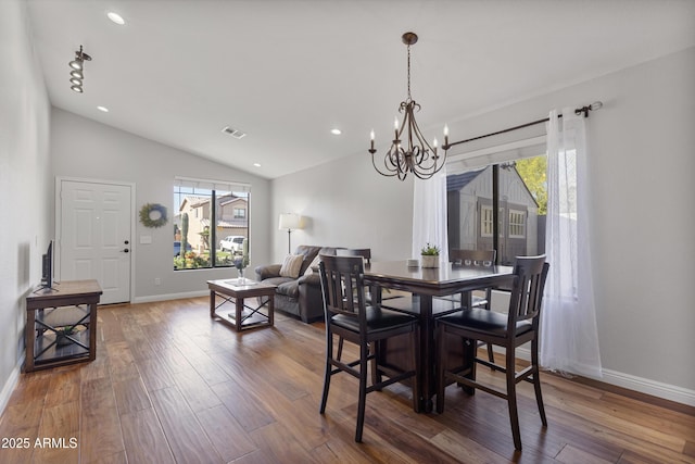 dining space with plenty of natural light, a chandelier, hardwood / wood-style floors, lofted ceiling, and baseboards