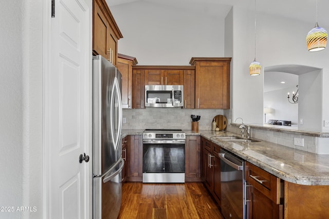 kitchen featuring stainless steel appliances, a sink, brown cabinets, and dark wood-type flooring