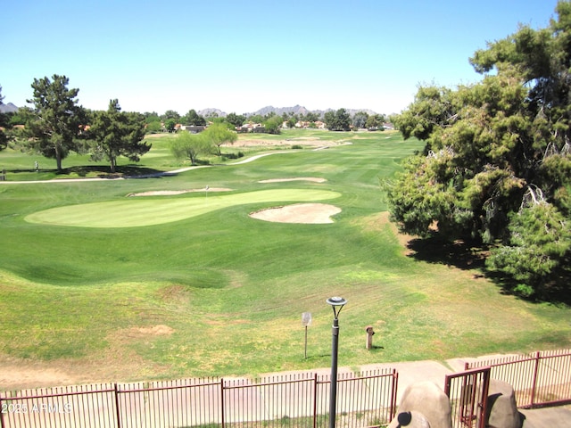 view of home's community featuring golf course view, fence, and a mountain view
