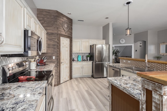 kitchen featuring sink, tasteful backsplash, decorative light fixtures, appliances with stainless steel finishes, and light hardwood / wood-style floors