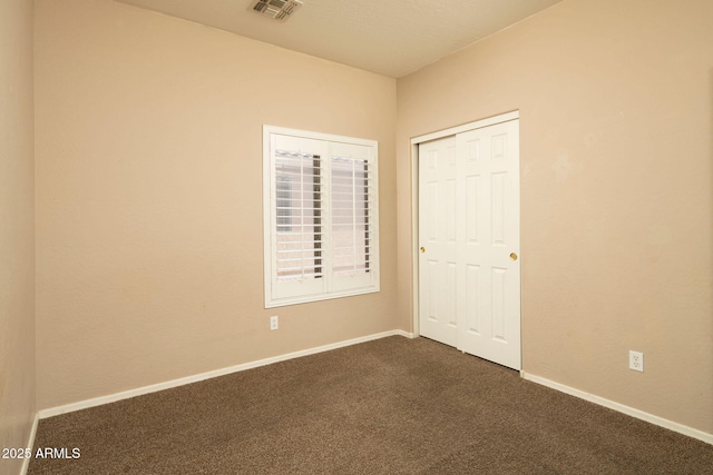 unfurnished bedroom with a closet and dark colored carpet