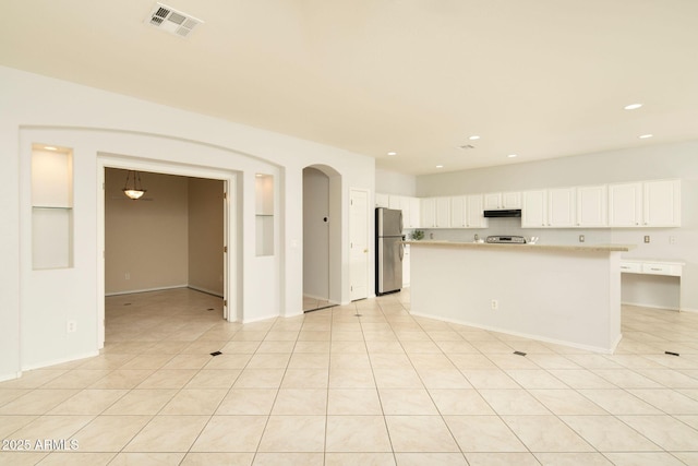 kitchen featuring light tile patterned floors, stainless steel fridge, white cabinets, and a kitchen island