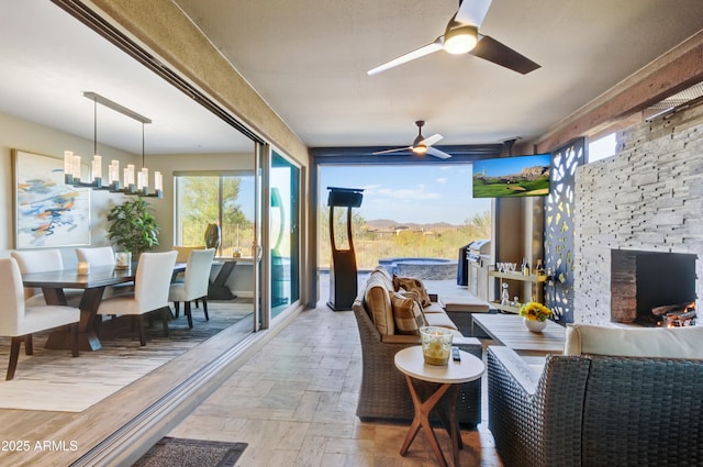 interior space featuring ceiling fan with notable chandelier, plenty of natural light, and a stone fireplace