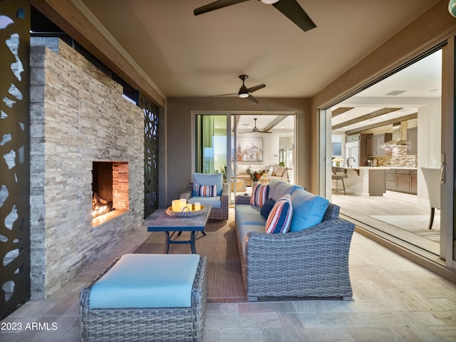 view of patio / terrace with ceiling fan, an outdoor kitchen, and an outdoor living space with a fireplace