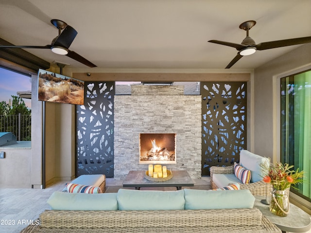 patio terrace at dusk with ceiling fan and an outdoor living space with a fireplace