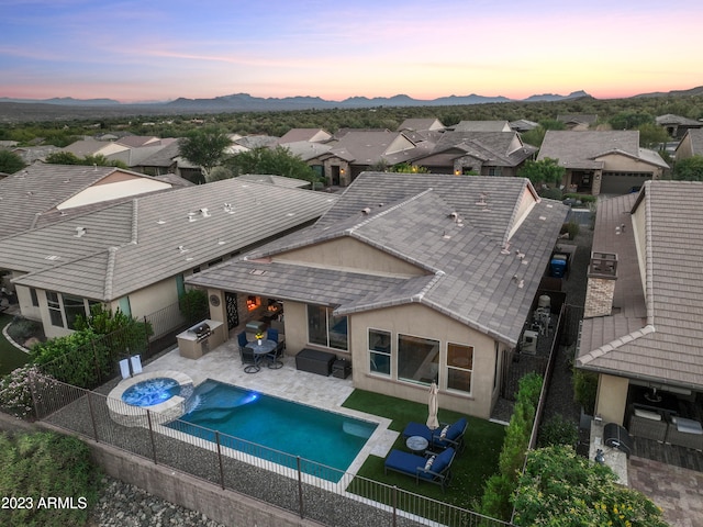 pool at dusk featuring an in ground hot tub and a patio